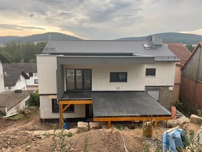 Anbau im Rohbau: das Haus steckt noch in Dämmplatten, die Terrasse liegt als abgedichtete Holzkonstruktion auf Stützen davor.