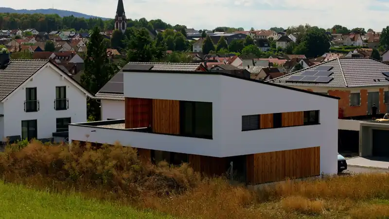 Das fertige Haus aus der Luft: Holzfassade, Flachdach, Photovoltaik auf den Nachbardächern.